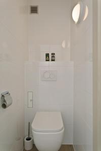 Baño blanco con aseo y pared blanca en Apartment V7, en Ostende
