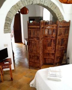 Cette chambre est dotée d'une voûte, d'un lit et de portes en bois. dans l'établissement Resort La Casa Dei Fiori, à Pantelleria