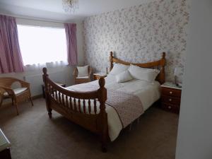 ein Schlafzimmer mit einem Holzbett und einem Fenster in der Unterkunft Glen B&B in Hamnavoe