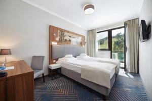 クリニツァ・ズドルイにあるHotel Pegazのベッド、デスク、窓が備わるホテルルームです。