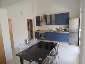 eine Küche mit blauen Schränken sowie einem schwarzen Tisch und Stühlen in der Unterkunft Apartments Naomi and Marsel in Trogir