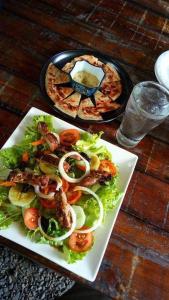 a plate of food with a salad and a pizza at Marius B&B & Hostel in Silang