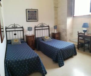 a bedroom with two beds and a table and a window at Masseria Gattamora in Uggiano la Chiesa