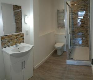 a bathroom with a sink and a toilet and a shower at Cotswold Aparthotel in Stroud