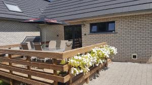 eine Holzterrasse mit einem Sonnenschirm, Stühlen und Blumen in der Unterkunft Le Duplex de la Raveline in Sart-lez-Spa