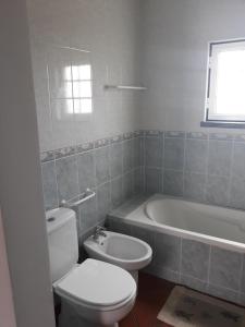 a bathroom with a toilet and a bath tub at I Ka Hale in Vila Nova de Milfontes