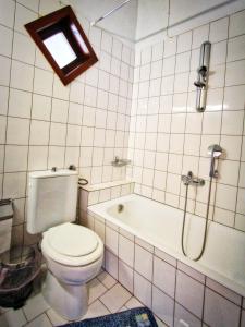 La salle de bains est pourvue de toilettes, d'une douche et d'une baignoire. dans l'établissement Glastres beach apartment, à PalaiónTsiflíkion