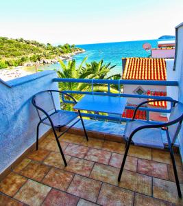 d'une table bleue et de chaises sur un balcon donnant sur l'océan. dans l'établissement Glastres beach apartment, à PalaiónTsiflíkion