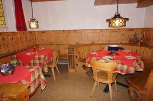 アローザにあるParadies 012の赤いテーブルクロスの椅子とテーブル2台が備わるレストラン