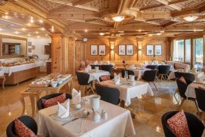 a restaurant with tables and chairs in a room at Swiss Alpine Hotel Allalin in Zermatt