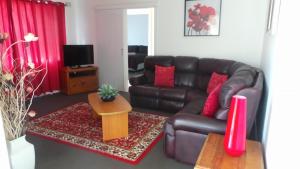 a living room with a brown leather couch and red pillows at The Garden House in Tamworth