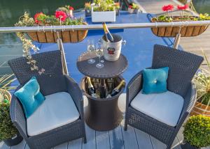 een patio met 2 stoelen en een tafel met wijnglazen bij Barge At Titanic in Belfast