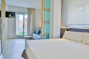 ロス・アルカサレスにあるApartamentos 525のベッドルーム(白いベッド1台、青いソファ付)