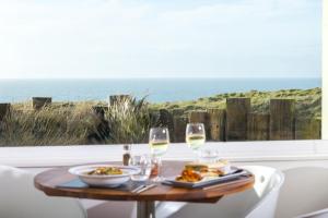 a table with food and wine glasses and a view of the ocean at Sands Resort Hotel in Newquay