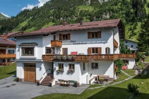 duży biały dom z górą w tle w obiekcie Haus Schrofenstein w Lech am Arlberg