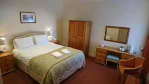 1 dormitorio con cama, escritorio y espejo en George & Dragon Hotel en Kirkbymoorside