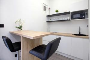a kitchen with a wooden counter and two black chairs at SENZACIJA apartments in Split