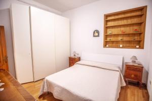 a bedroom with a white bed and a cabinet at La casa di Francesca in Castelnuovo Berardenga
