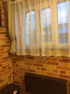 a brick wall with two windows with white curtains at Zolotoi Bereg 31 in Odesa