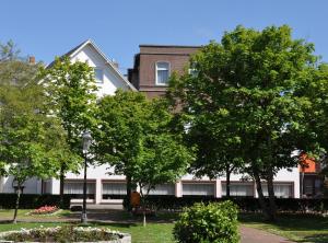 un bâtiment blanc avec des arbres devant lui dans l'établissement Hotel Graf Waldersee, à Borkum