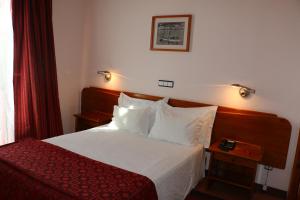 a hotel room with a bed and a red curtain at Apartamentos Turisticos Verdemar in Horta