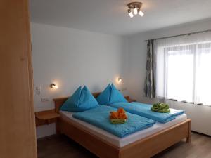 sypialnia z łóżkiem z niebieskimi poduszkami i oknem w obiekcie Appartement Wildkogelblick w mieście Neukirchen am Großvenediger