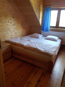 a bed in a wooden room with a window at Cztery Pory Roku in Sarbinowo