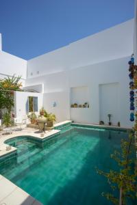 een zwembad met blauw water in een huis bij Dar R'Bat, Maison d'Hôtes de charme in Nabeul