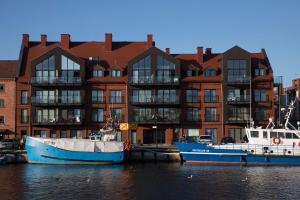 dwie łodzie zacumowane w wodzie przed budynkiem w obiekcie Apartamenty Port Ustka w Ustce