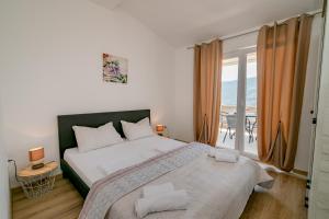 a bedroom with a large bed and a balcony at Vasic Apartments in Herceg-Novi