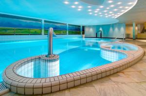 a large swimming pool in a hotel lobby with a large pool at Landgoed De Holtweijde in Lattrop