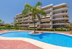 a hotel with a palm tree in front of a swimming pool at Fantastic Apartment Next To Guadalmina Golf Course In Marbella in Marbella