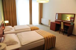 pokój hotelowy z dwoma łóżkami, biurkiem i lustrem w obiekcie Hotel Vis a Vis Łańcut w Łańcucie