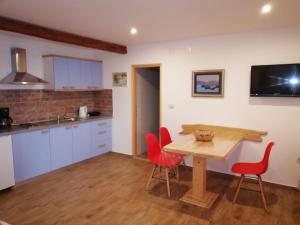 a kitchen with a wooden table and red chairs at Apartments Blue & Green in Mošćenička Draga