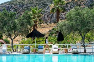 una mujer caminando por la piscina en un resort en Akra Morea Hotel & Residences en Monemvasía