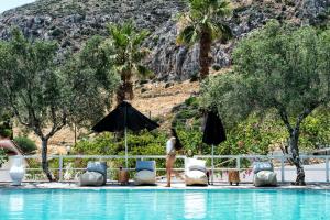 a woman standing next to a pool at a resort at Akra Morea Hotel & Residences by GHH in Monemvasia