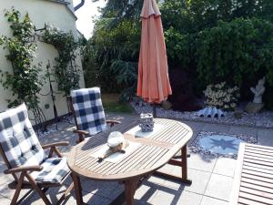 un patio con mesa, sombrilla y 2 sillas en OSTSEEFERIEN IN LICHTENHAGEN-DORF FERIENWOHNUNG, en Elmenhorst Anteil