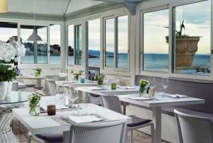 a restaurant with white tables and chairs and windows at Villa delle Palme in Santa Marinella