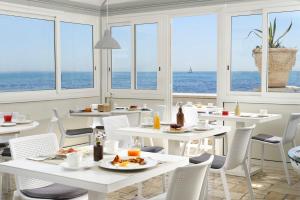 a restaurant with white tables and chairs and the ocean at Villa delle Palme in Santa Marinella