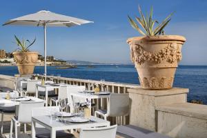 a restaurant with white tables and chairs and the ocean at Villa delle Palme in Santa Marinella