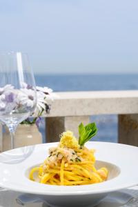 a plate of pasta on a table with a glass of wine at Villa delle Palme in Santa Marinella