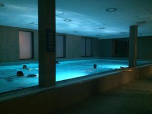 two people swimming in a swimming pool at night at Hotel Panská Zahrada in Dobřichovice