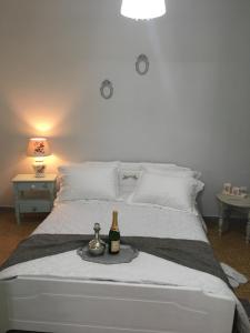 Una cama blanca con una botella de vino. en Villa Ermilia, en Kerveli