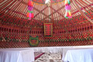 a large yurt with white tables and colorful decorations at Адилет in Cholpon-Ata +51 photos