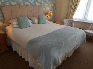 a bedroom with a large white bed with pillows at Tregonwell House - Guest House in Minehead