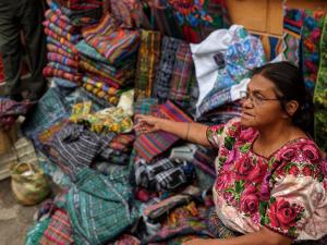 a woman sitting in front of a pile of ties at Hotel Paraíso in San Pedro La Laguna
