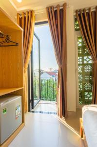 Habitación con una gran puerta de cristal y balcón. en D Central Hoi An Homestay, en Hoi An