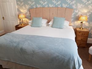 a bedroom with a large white bed with blue pillows at Tregonwell House - Guest House in Minehead