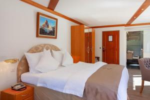 ein Schlafzimmer mit einem großen weißen Bett in einem Zimmer in der Unterkunft Hotel Beau Rivage in Zermatt
