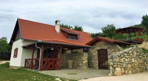 una casa con techo rojo y pared de piedra en Kikapcsol-lak, en Pécsely